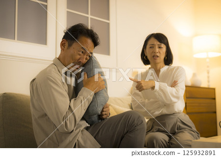 A middle-aged couple arguing in the living room at night A middle-aged couple arguing in the living room at night 125932891