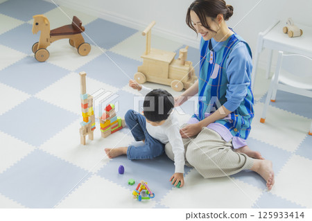 一個玩積木的孩子和一個穿著圍裙的女人 125933414