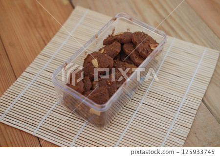 a clear plastic container filled with chocolate almond cookies 125933745