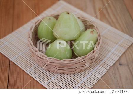a woven basket filled with green water apples a woven basket filled with green water apples 125933821