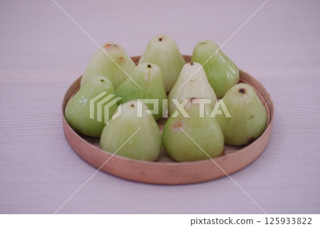 a woven basket filled with green water apples 125933822