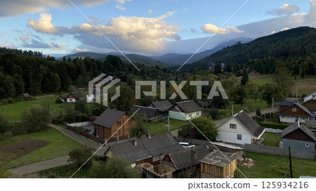 Scenic mountain village in Ukraine surrounded by lush forests and rolling hills during early evening. Scenic mountain village in Ukraine surrounded by lush forests and rolling hills during early evening. 125934216