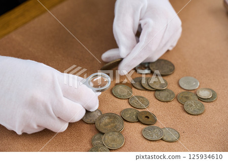 A female appraiser appraising old coins 125934610