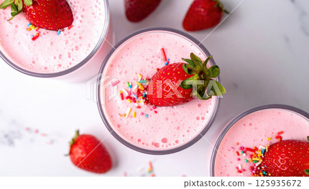 Strawberry milkshakes topped with fresh strawberries and colorful sprinkles on white surface 125935672