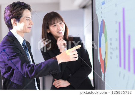 穿著西裝的年輕男女確認示範內容 125935752