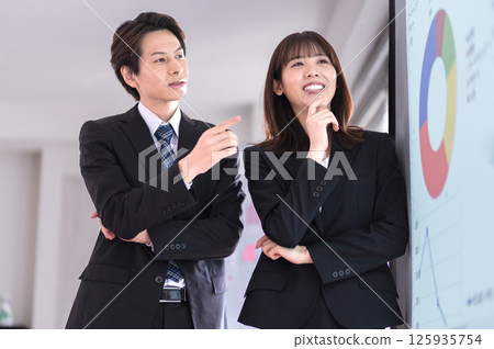 穿著西裝的年輕男女確認示範內容 125935754