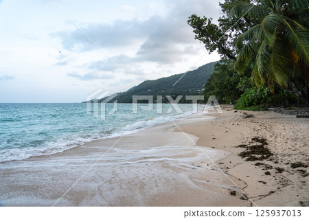 Anse Beau Vallon tropical beach in cloudy weather, ocean waves out of season on Mahe island 125937013