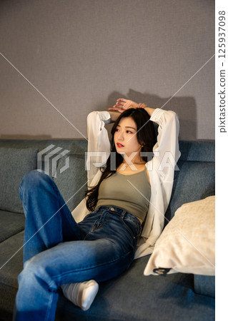 A woman in denim relaxing in a room at night 125937098