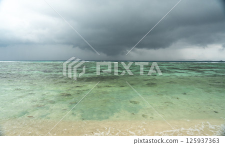 Dark tropical storm over turquoise ocean near Seychelles islands, with dramatic sky, rough water 125937363