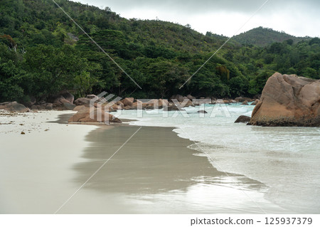 Tropical beach on Praslin island, Seychelles, with turquoise ocean waves, lush jungle hills 125937379
