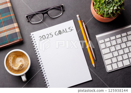 Elegant leather desk setup with laptop, coffee, stationery, and a notepad labeled 2025 Goals Elegant leather desk setup with laptop, coffee, stationery, and a notepad labeled 2025 Goals 125938144