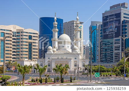 White mosque between modern highrises in urban Dubai contrast White mosque between modern highrises in urban Dubai contrast 125938259