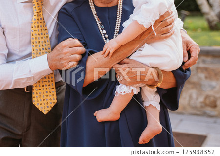 Grandparents Holding Grandchild at Baptism Celebration 125938352