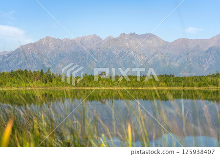 Mountain lake with calm water, surrounded by forest Mountain lake with calm water, surrounded by forest 125938407