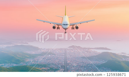 Passenger airplane on landing approach over a coastal city during scenic sunset or sunrise golden hour 125938671