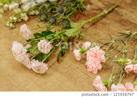 Florist arranging pink carnations and chrysanthemums on wooden table, mothers day 125938797