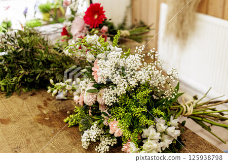 Florist creating bouquet with fresh flowers on wooden table, Mothers day Florist creating bouquet with fresh flowers on wooden table, Mothers day 125938798