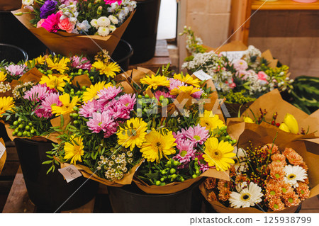 Colorful bouquets of fresh flowers wrapped in brown paper are displayed in black buckets, Mothers day Colorful bouquets of fresh flowers wrapped in brown paper are displayed in black buckets, Mothers day 125938799