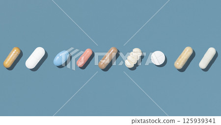 Medical capsules and pills in a line on blue top view, hard shadow. Medicine and healthcare Medical capsules and pills in a line on blue top view, hard shadow. Medicine and healthcare 125939341