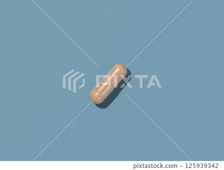 Beige Medical capsule on blue top view, hard shadows. Taking dietary supplements Beige Medical capsule on blue top view, hard shadows. Taking dietary supplements 125939342