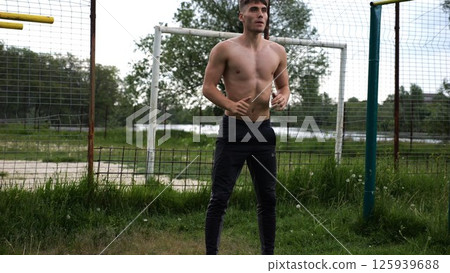 Male shirtless athlete doing squats at sports ground. Young sportsman working at summer nature. Strong sporty man exercising outdoor. Concept of active and sportive lifestyle. Slow motion 125939688