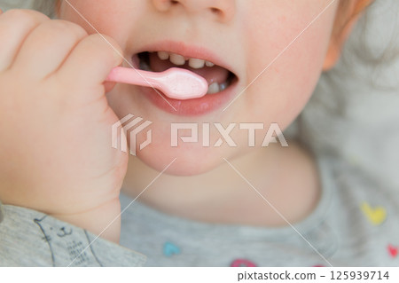 Cute little child in bathroom.  Girl cleaning the teeth with pink brush. 125939714