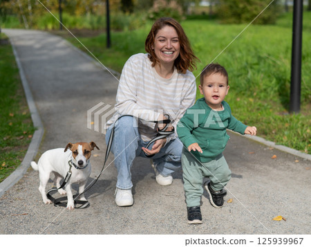 Caucasian woman walks in the park with her one-year-old son and Jack Russell Terrier dog. Caucasian woman walks in the park with her one-year-old son and Jack Russell Terrier dog. 125939967