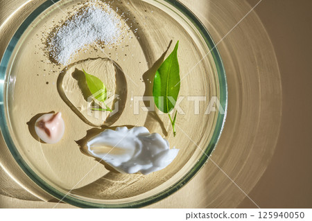 Various cosmetics in a petri dish on a beige background. 125940050