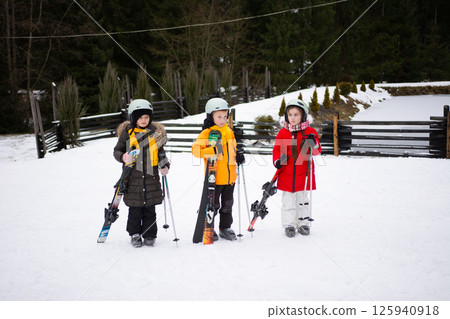 Young skiers in colorful attire explore a snowy landscape during a winter ski lesson in a picturesque mountain resort amid lush pine trees Young skiers in colorful attire explore a snowy landscape during a winter ski lesson in a picturesque mountain resort amid lush pine trees 125940918
