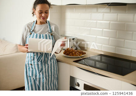 Woman Preparing Breakfast in a Bright Modern Kitchen with Tasty Croissants 125941436