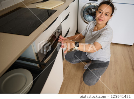 Woman Organizing Kitchen Drawers in a Modern Home Interior Woman Organizing Kitchen Drawers in a Modern Home Interior 125941451
