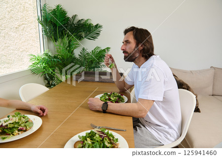 Man Enjoying A Healthy Salad Meal at A Dining Table 125941460