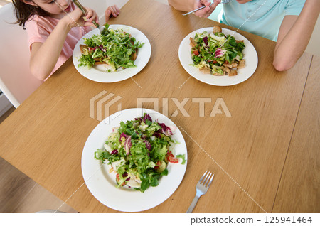 Family Enjoying Healthy Vegetarian Meal Together at Home on a Sunny Day Family Enjoying Healthy Vegetarian Meal Together at Home on a Sunny Day 125941464
