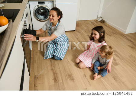 Mother Cooking with Children in Modern Kitchen on Sunny Morning 125941492