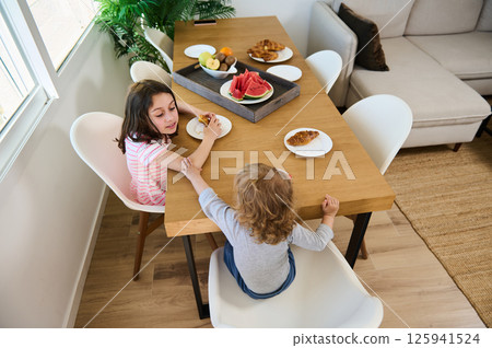 Children Enjoying a Healthy Breakfast at a Home Dining Table Children Enjoying a Healthy Breakfast at a Home Dining Table 125941524