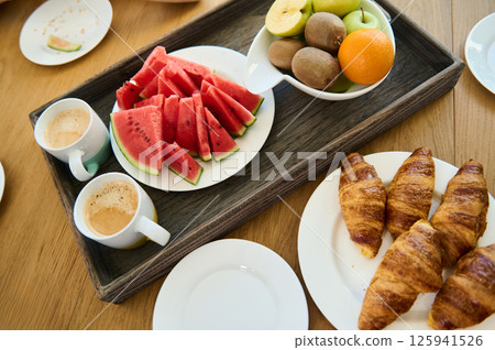 Healthy Breakfast With Fresh Fruits, Croissants, and Coffee on Wooden Tray 125941526