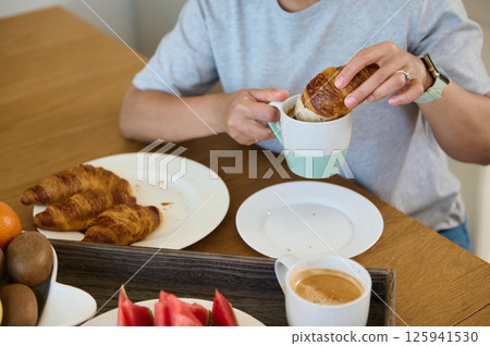 Woman Enjoying a Cozy Breakfast with Croissants and Coffee at Home Woman Enjoying a Cozy Breakfast with Croissants and Coffee at Home 125941530