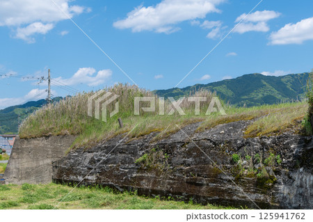 The remains of the northern air raid shelter of the former Japanese military's Yanagimoto Airfield, standing in a rice paddy area before rice planting The remains of the northern air raid shelter of the former Japanese military's Yanagimoto Airfield, standing in a rice paddy area before rice planting 125941762