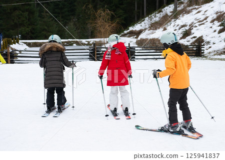 Exciting winter day with young skiers learning to conquer the snowy slopes in a scenic alpine resort during a sunny afternoon 125941837
