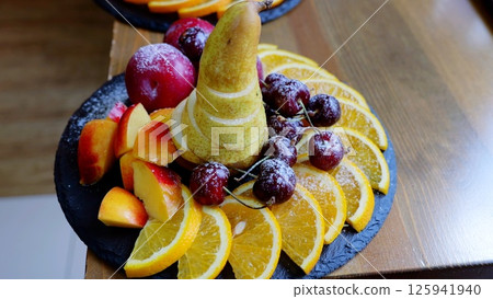 Colorful sliced fruitspear, peach, plum, cherry, orangesprinkled with powdered sugar, presenting fresh, sweet dessert platter for healthy indulgence 125941940