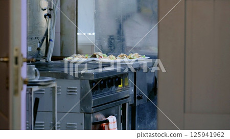 Commercial kitchen stove displaying multiple plated meals during peak lunchtime service, waiting for restaurant servers 125941962