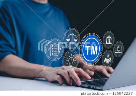 TM, Trademark and intellectual property protection concept. Businessman working on laptop with virtual icons representing trademarks, intellectual property rights, legal scales, security, innovation, TM, Trademark and intellectual property protection concept. Businessman working on laptop with virtual icons representing trademarks, intellectual property rights, legal scales, security, innovation, 125942227