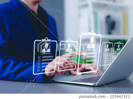 Recruitment and candidate selection concept. Businessman interacts with digital interface with multiple candidate profiles on laptop. Represents online recruitment, HR technology, hiring process, 125942351