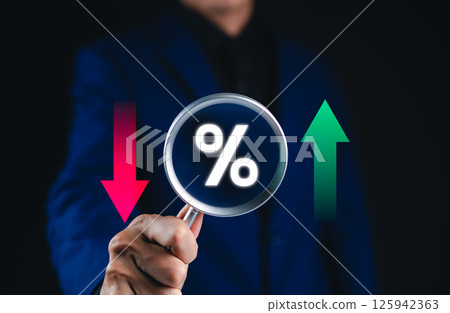 Financial interest rate and market trends concept. Businessman holding magnifying glass with percentage symbol, with red and green arrows, financial market fluctuation, interest rates, economic trend, 125942363