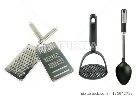 Grater, shredder, potato masher and large spoon isolated on white background. Grater, shredder, potato masher and large spoon isolated on white background. 125942732