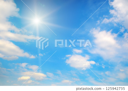 Bright sun and white clouds in clear blue sky 125942735