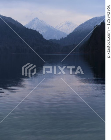Tranquil lake reflecting snowy mountains in a serene landscape at dusk 125942956