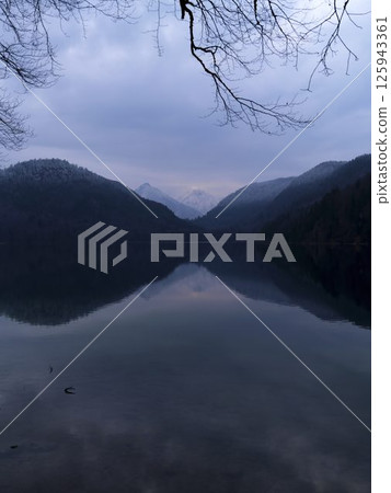 Tranquil lake reflecting mountains at dusk with serene atmosphere and soft colors in nature Tranquil lake reflecting mountains at dusk with serene atmosphere and soft colors in nature 125943361