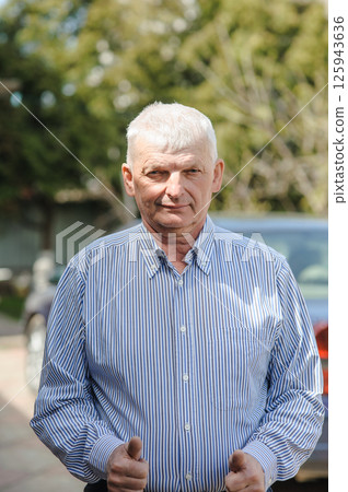 The gray-haired old man is dressed for a walk. A mature man is breathing fresh air. 125943636