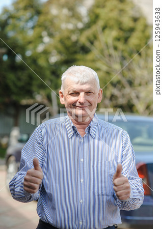 The gray-haired old man is dressed for a walk. A mature man is breathing fresh air. The gray-haired old man is dressed for a walk. A mature man is breathing fresh air. 125943638